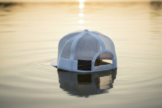 White mesh laundry bag with a black handle on a textured white surface